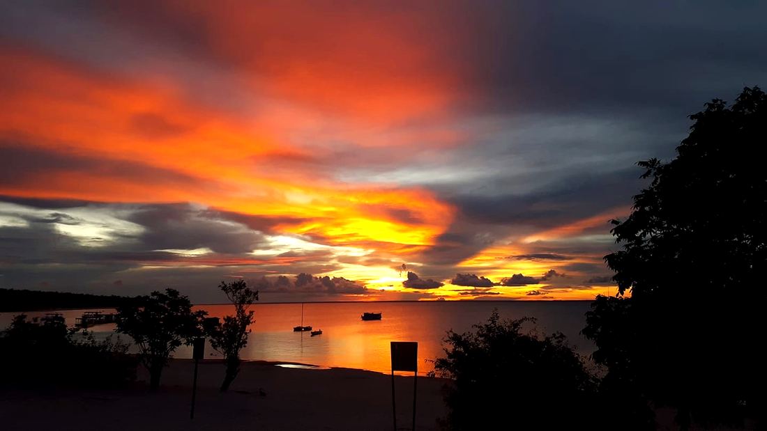 Céu de fogo ao pôr do sol sobre o rio Tapajós, com barcos ancorados
