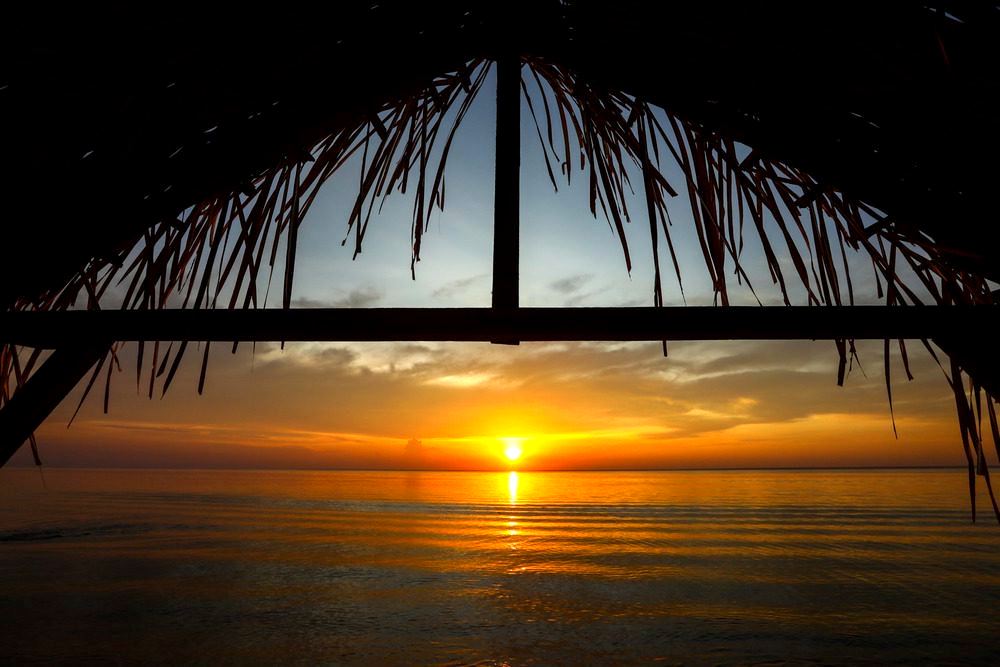 Pôr do sol emoldurado pelo teto de palha